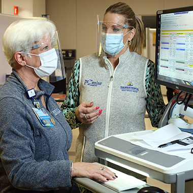 Sarah Rasmussen, R.N., and Michelle Christ, physician liaison, review the day’s vaccination schedule. They are part of the Suburban Hospital team supporting day-to-day operations of the community clinic.  