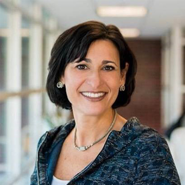 head shot of CDC director Rochelle Walensky, wearing a chic necklace and earrings, smiling in a hallway. 