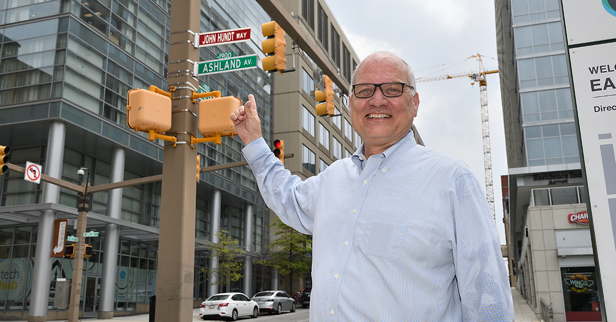 John Hundt points to the street sign "John Hundt Way".