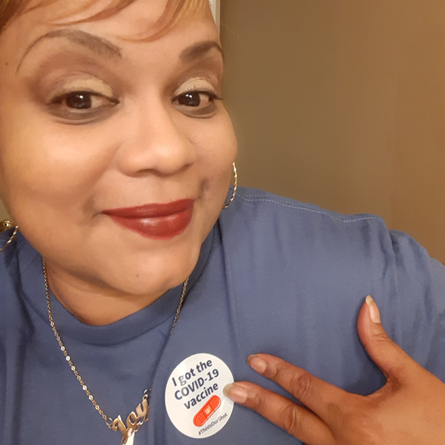 Photo of Johnson pointing to vaccine sticker.
