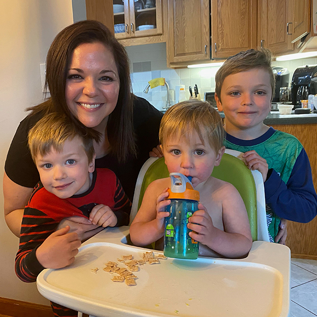 Kim Rowsome smiles with her three young sons in her kitchen