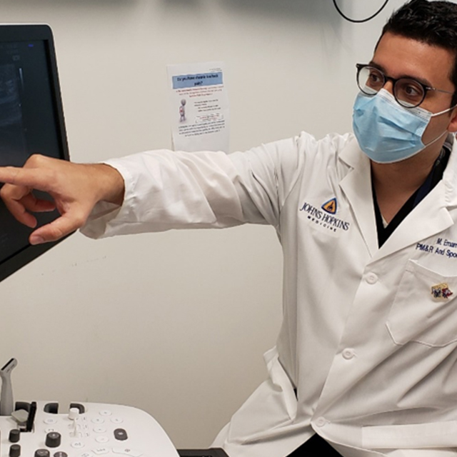 Mo Emam points at a screen while performing an ultrasound.