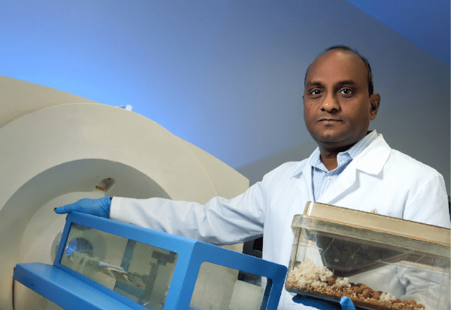 Sridhar Nimmagadda standing next to a positron emission tomography machine.