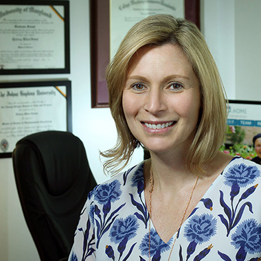 Quincy Samus, in her office, wearing a white blouse with blue flowers on it