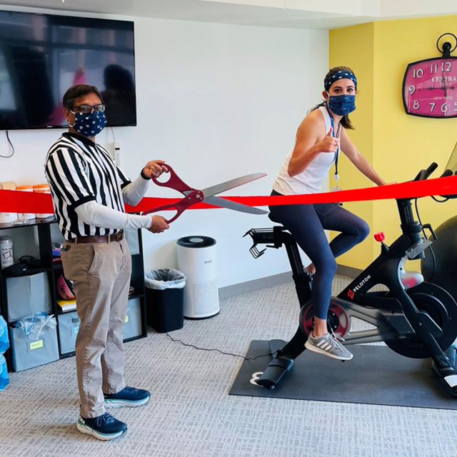 Cheered on by Sanjay Desai, former Osler Medical Residency director, then Osler medical resident Eva Valilis is the first person in the program to try out the exercise bike purchased through funds from the American Medical Association’s Reimagining Residency grant. Photo credit: Joanna Wang