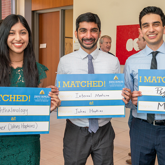 Three students stand with their match cards