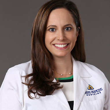 Kelly Lafaro, in a formal portrait, wearing a white lab coat and black and white blouse