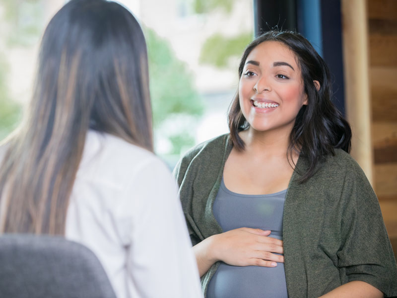 A pregnant woman speaks with her doctor at an appointment