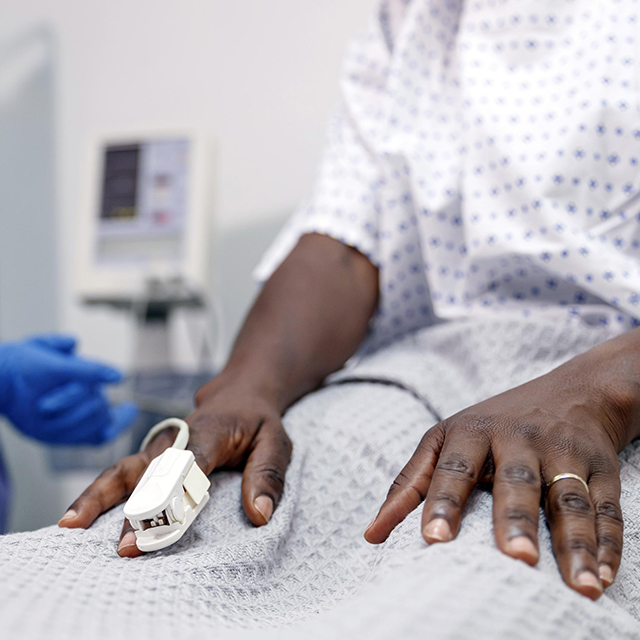 Photo of a woman's hand with a heart monitor on her index finger.
