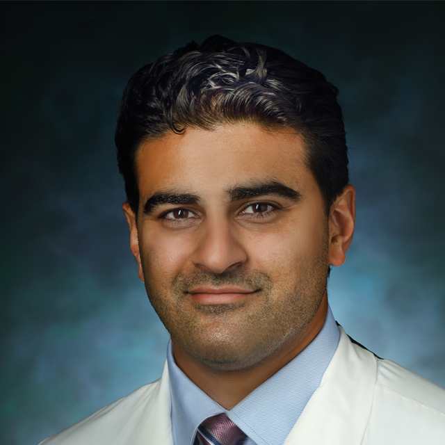 Head shot of Dr. Ahmad, wearing a shirt, tie and white coat. 