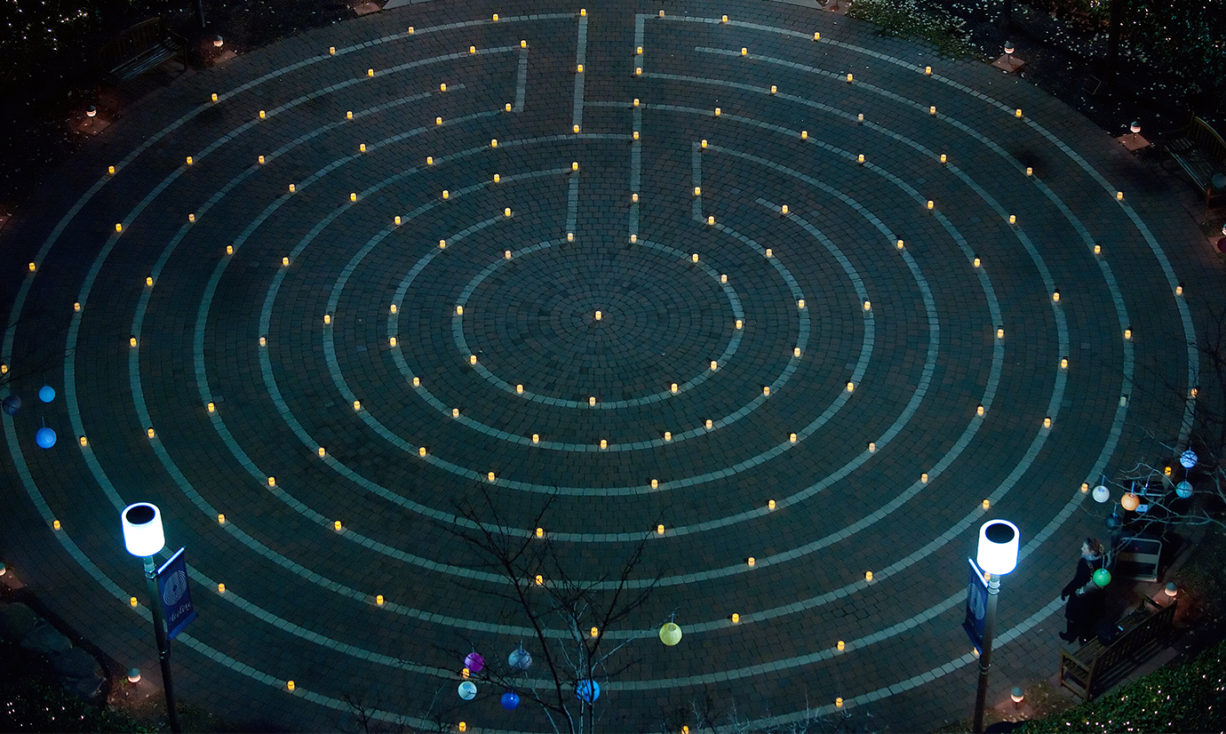 A wide image of the whole labyrinth lit up by candles. 