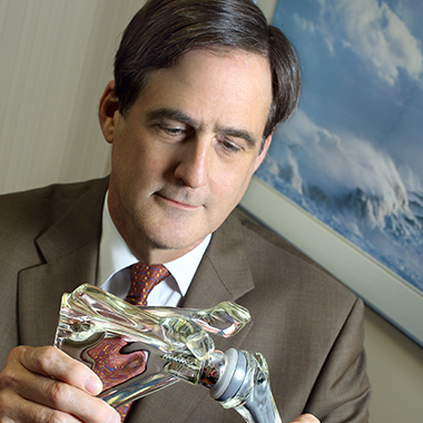 Edward McFarland, wearing a brown suit, holding a plastic shoulder model