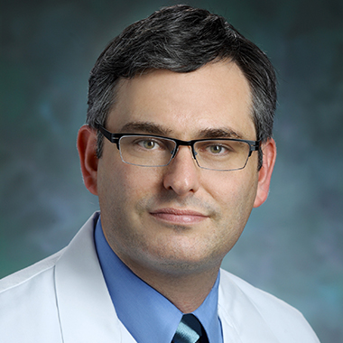 Laryngologist Lee Akst in white coat, posing for formal portrait