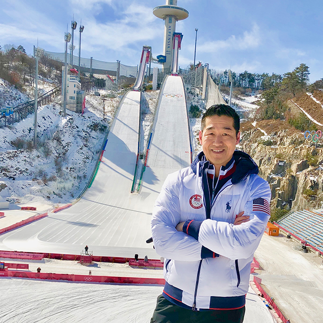 Andrew Chen stands on a ski slope in ski gear.