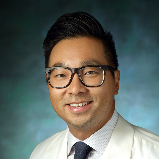 Robin Yang smiling in a white coat. 
