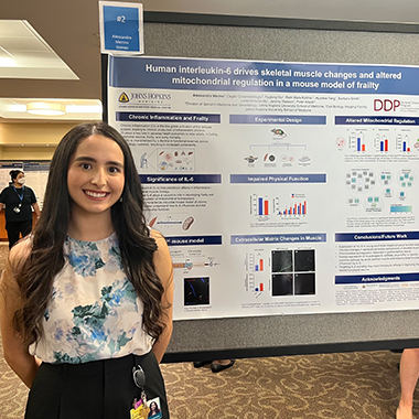 Alessandra Merino Gomez stands in front of her poster board at a conference