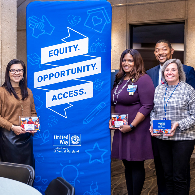 United Way award winners stand with a pop-up banner.