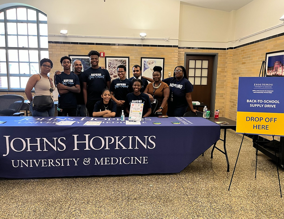 Interns from the 2023 Johns Hopkins Summer Jobs Program team up with members of The Community Group, Inc., to collect resources for city schools.