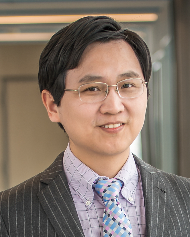 A portrait of Tinglong Dai wearing a striped suit.