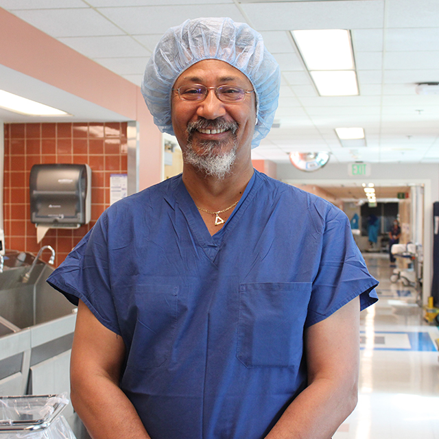 Allen Forney stands in a hallway in scrubs