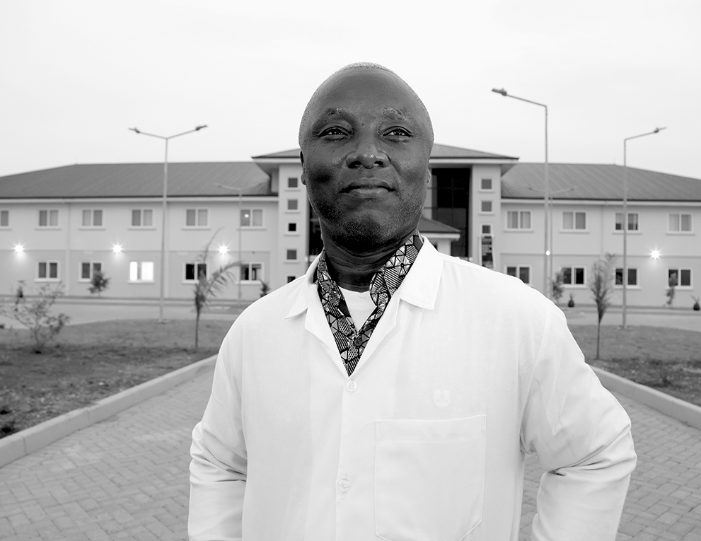Boahene stands in front of the new hospital building. His arms at his side like a superhero.