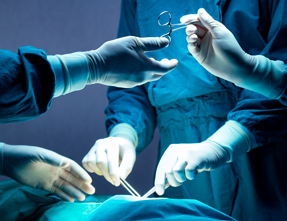 A surgeon is offered a pair of scissors during a surgery.