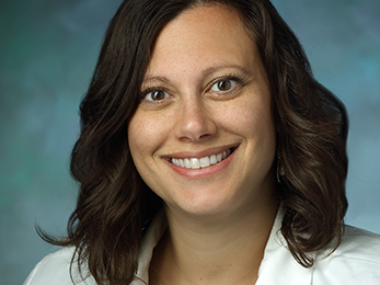 Traci Speed in physician's white coat, smiling for a formal portrait.