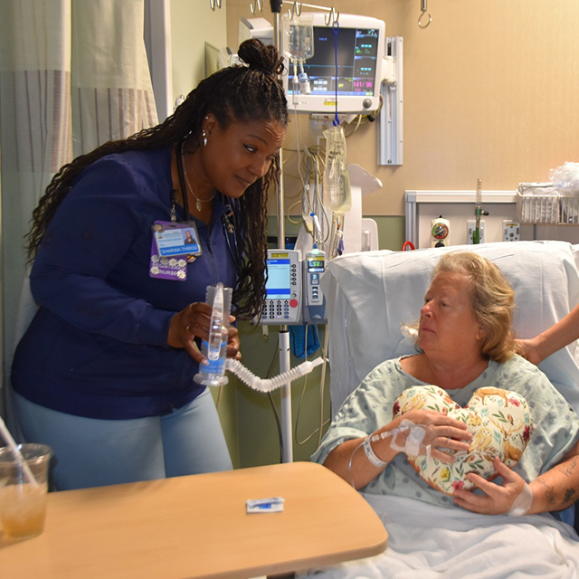 Patient Fran holds a heart-shaped pillow given to her by students and nurse Zhen Yuan