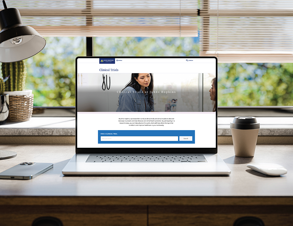 A laptop on a desk shows the new clinical trials database website