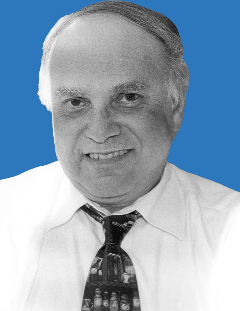 Black and white portrait of a doctor smiling in front of a blue background.