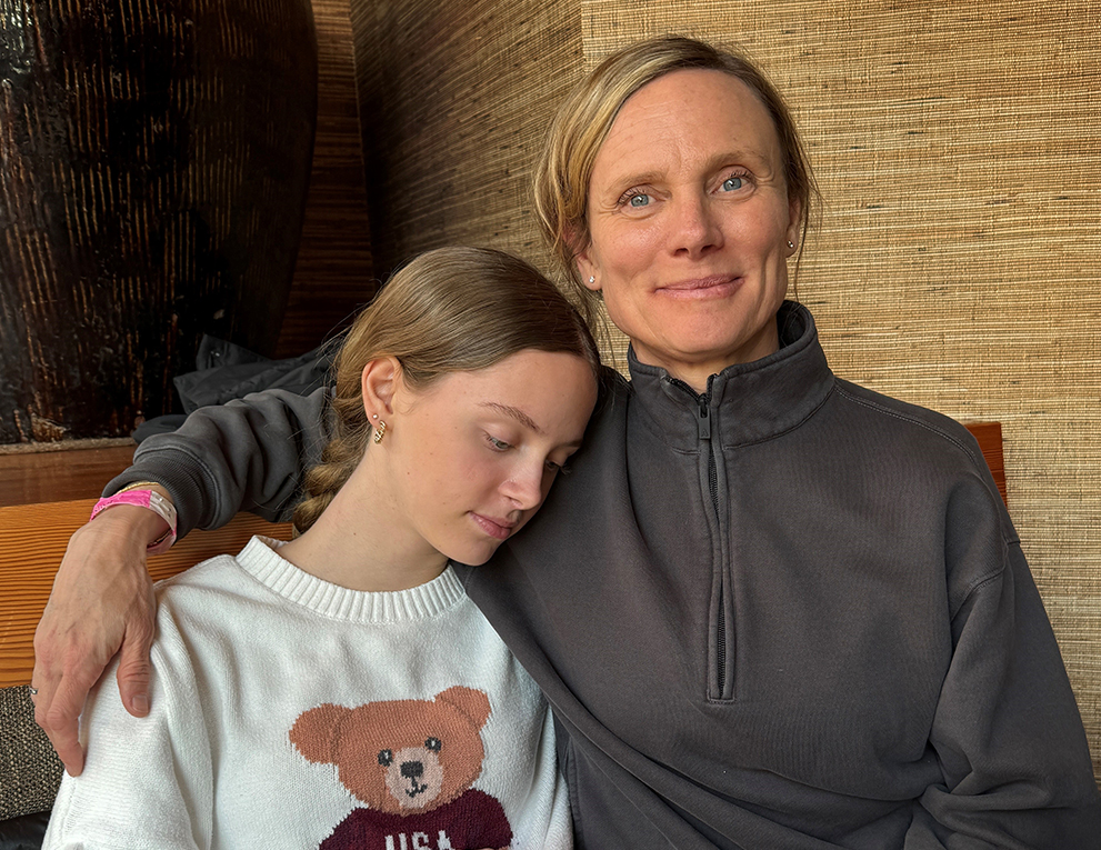 A resting daughter rests her head on her mom's shoulder.