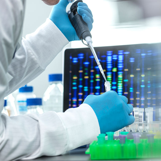 A researcher using a pipette to add liquid to a test tube.