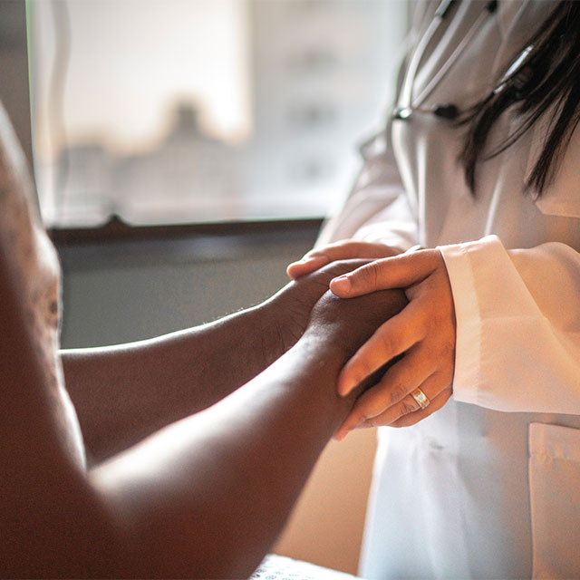A doctor holding the hands of a patient.