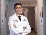 Savya Thakkar, M.D. standing in a hospital hallway