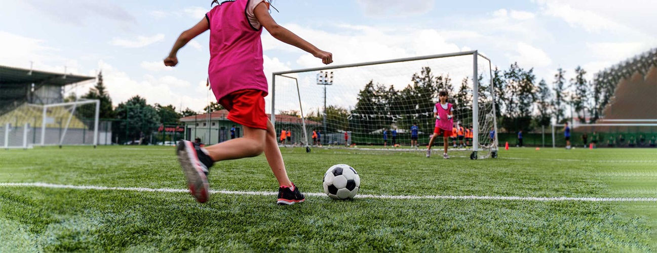 girl kicking a soccer ball into the goal