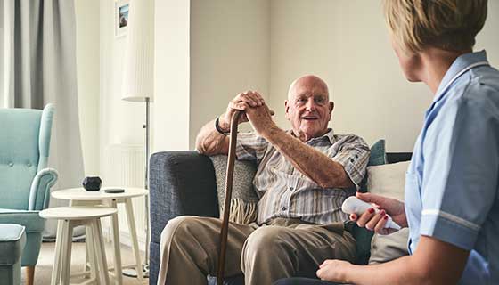 senior man with cane smiling at caretaker