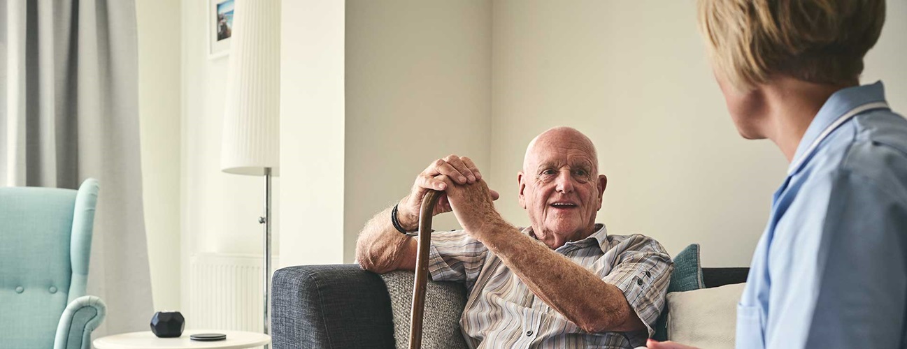Senior man with cane smiling at caretaker