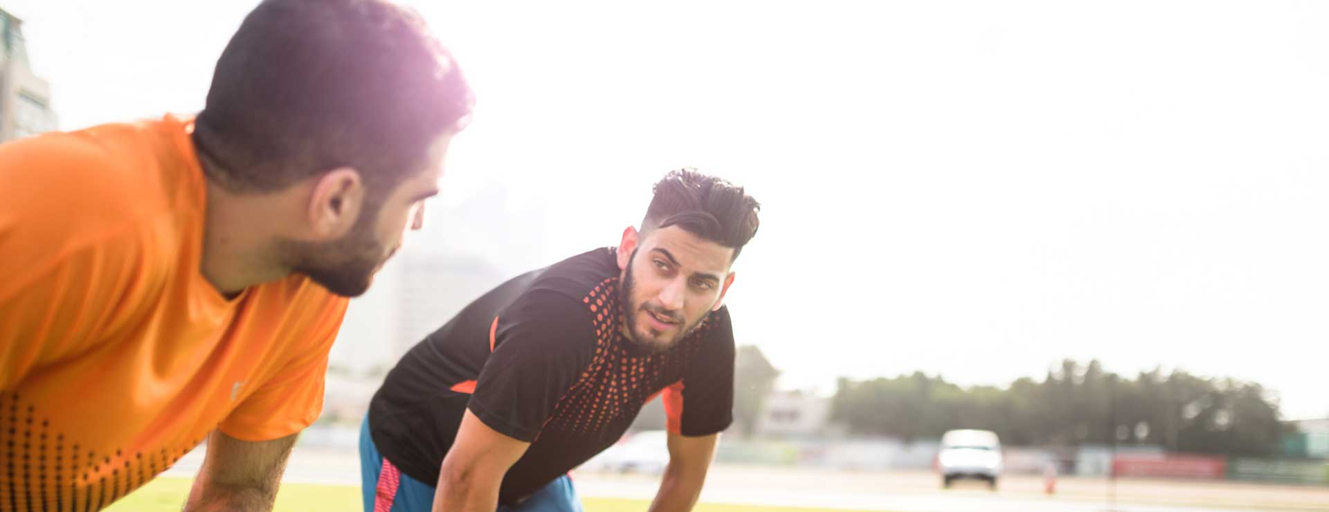 Two young men pause their soccer game to stretch.