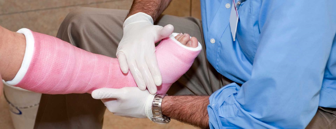 Doctor examining a patient's knee in a cast.