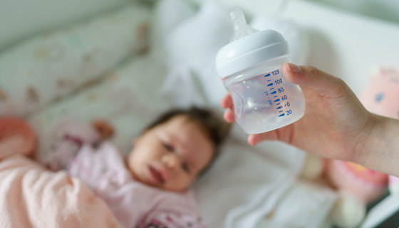 Woman holding empty baby bottle over her baby