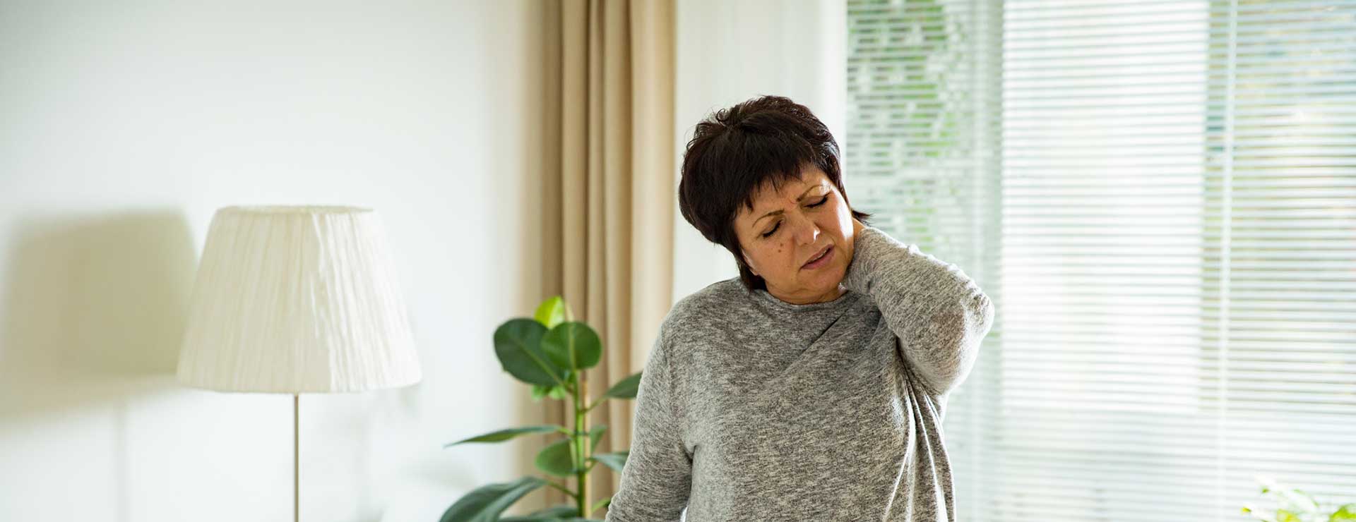 A woman rubs her neck in pain.