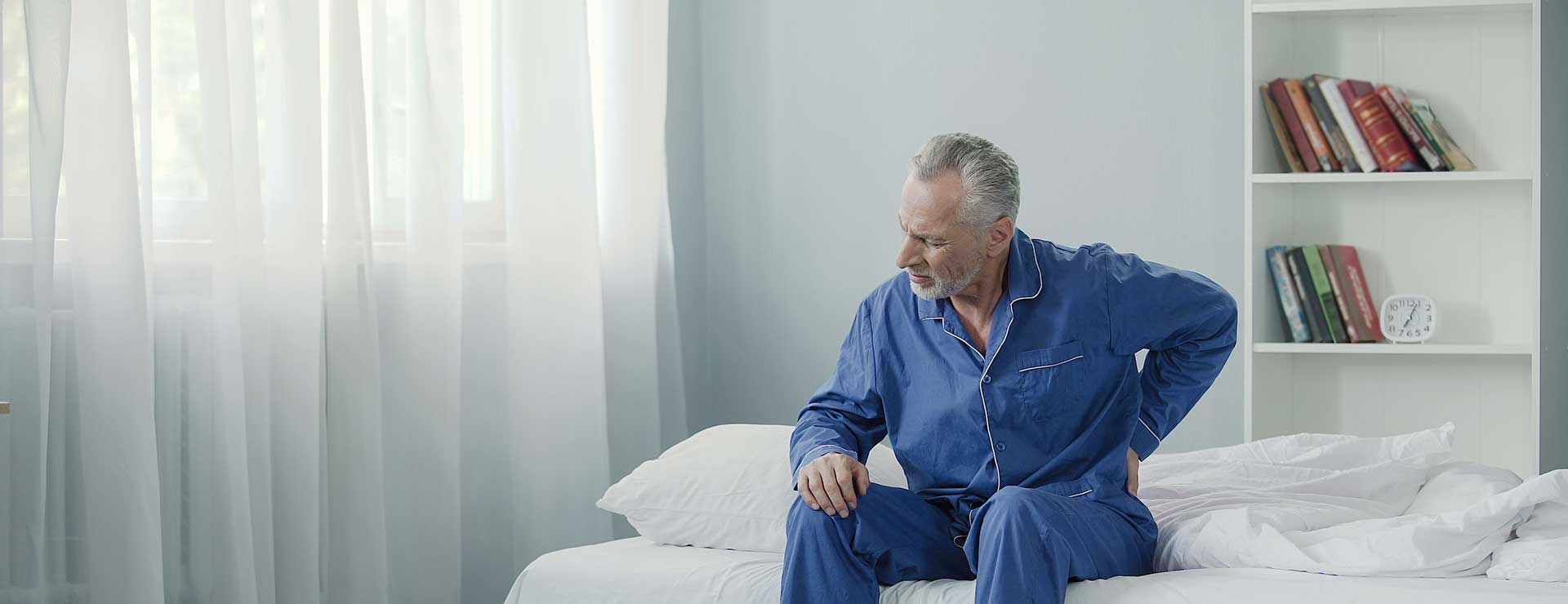 A man experiences back pain while getting out of bed.
