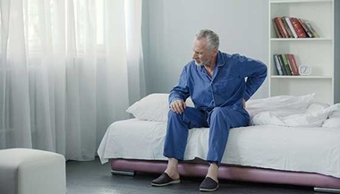 A man experiences back pain while getting out of bed.