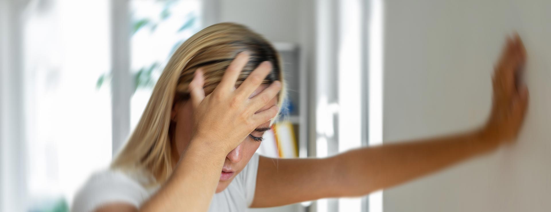 Woman with headache leaning against wall