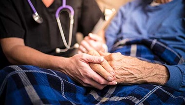 hospice nurse holding elderly patient's hand