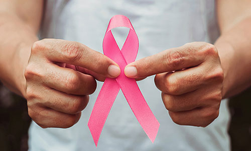 masculine hands holding a pink breast cancer ribbon