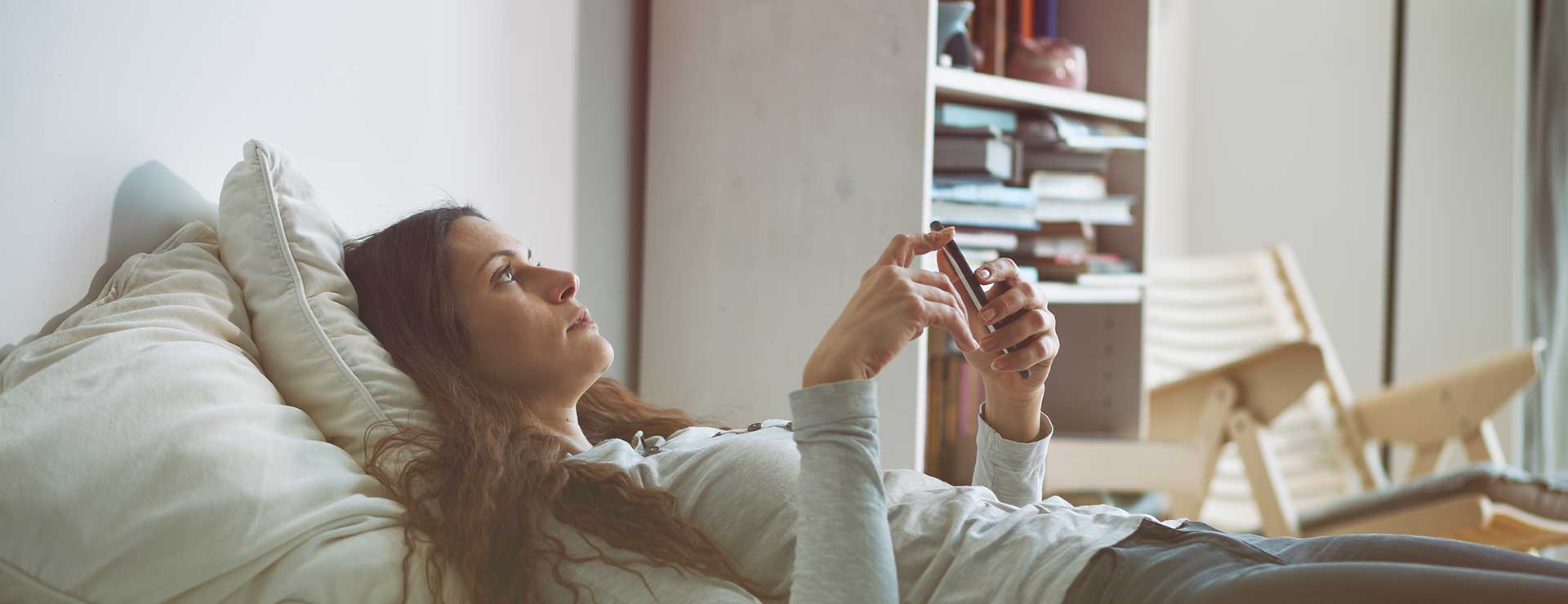 woman laying on bed searching on her phone
