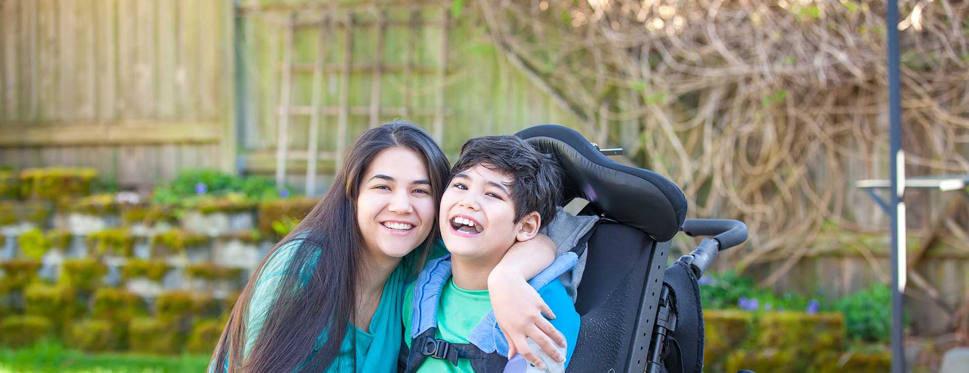 girl hugging brother in wheelchair