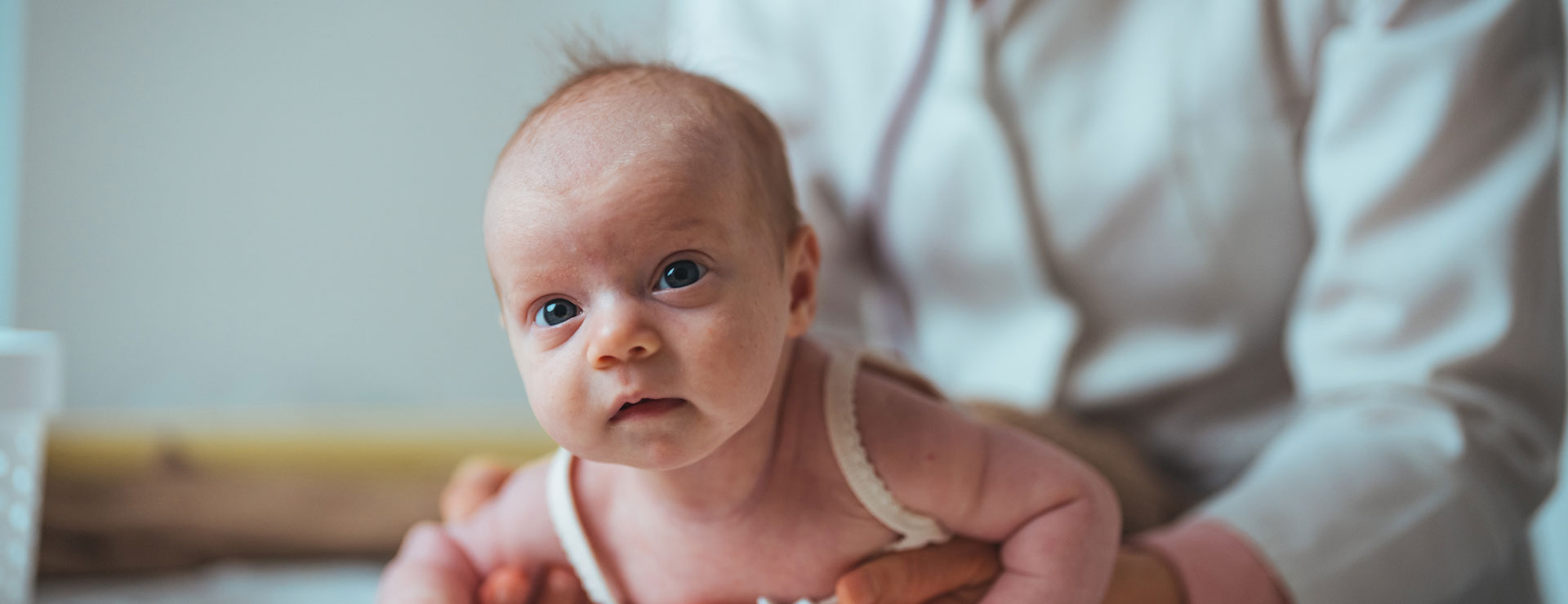 baby on stomach being observed by pediatrician. 