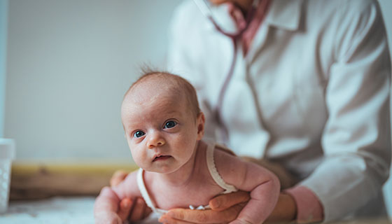 baby on stomach being observed by pediatrician. 